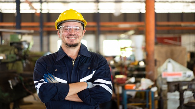Smiling serviceman in blue clothes and yellow helmet working with HVO biofuel