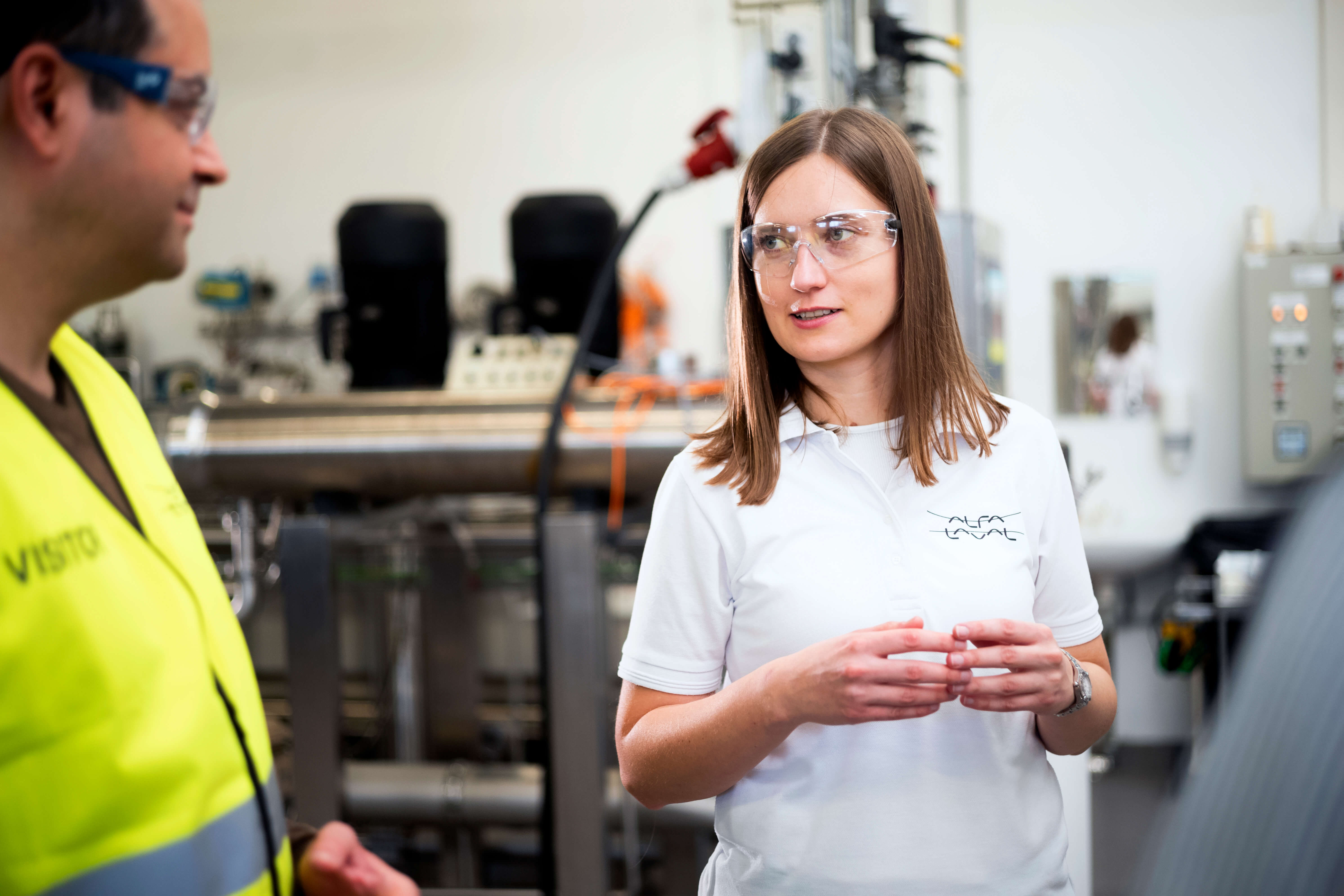 Young female engineer is talking to two men in factory 3